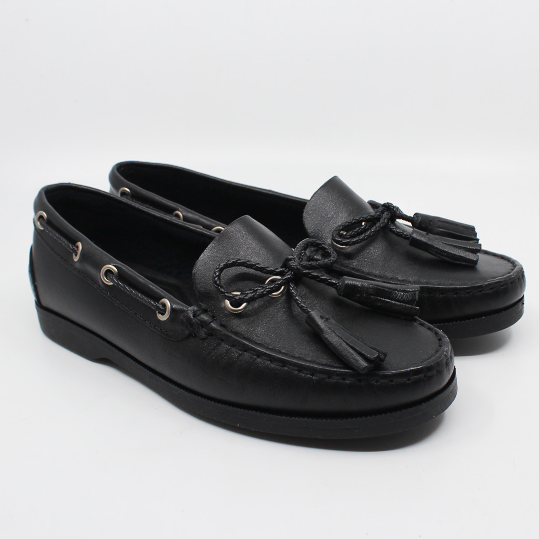Pair of Rebecca Allen The Captain Boat tasseled boat shoes in Black leather with black soles, shown from the front three-quarter angle