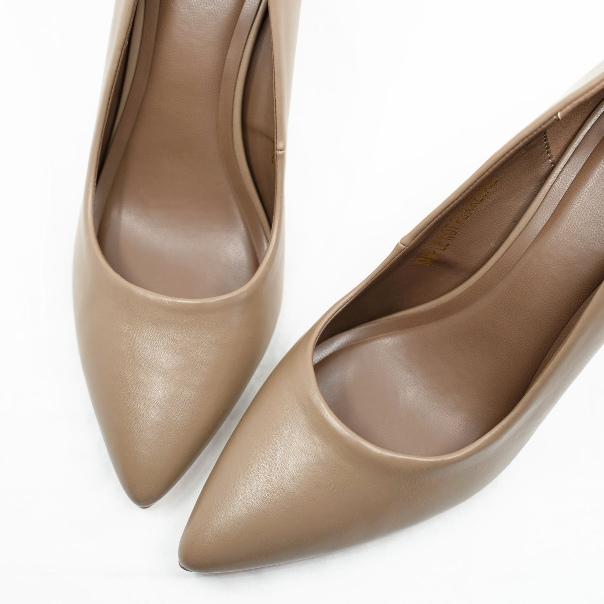 Overhead close-up of the pointed toes on a pair of Rebecca Allen The Point pumps in Nude II, a warm taupe